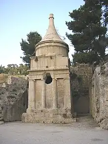 A rock-cut tomb in the shape of a temple with a large hole cut into it