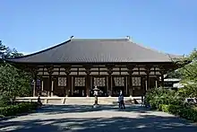 Wooden building with white walls built on a stone platform.