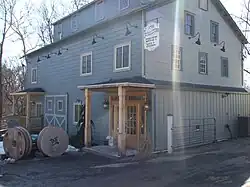 A brown building lined by wooden fence, lit sharply from the East by the early morning sun