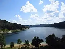 A reservoir surrounded by green forested hillsides.