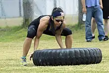 Woman lifting a 200 pound tyre - bent knees essential to avoid back strain.