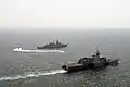 A rigid-hull inflatable boat from the LCS USS Freedom takes a visit, board, search and seizure team to the Malaysian frigate KD Jebat during a compliant boarding exercise.