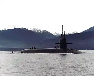 Submarine in bay with valleys and snow-capped mountains in the background.