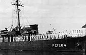 Officers and crew line the rails while in port.