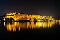 Night view of Udaipur city palace by lake Pichola, a view from Ambrai ghat.