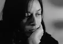 B&W close-up photo of a woman gazing to the side, holding her chin with her left hand