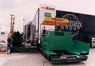 A road paver.  The rollers at the front push the truck along while unloading.  The slat conveyor in the middle drags the asphalt to the back.