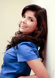 Vanessa Giácomo leaning to wall in blue blouse