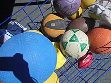 A variety of balls in a cage