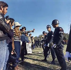 A young woman demonstrator offers a flower to a military police officer at the March on the Pentagon, 1967