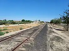 A well-worn set of train tracks with farm fields in the background