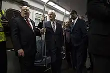 Wiedefeld, Larry Hogan, and Ike Leggett all stand and hang onto railings while riding a train on the Metro's Red Line