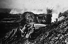 Photo of a German assault on Fort Vaux. In the foreground four German soldiers man two machine guns, while the fort can be seen in the background.