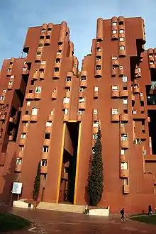 irregularly-shaped, multi-story red building with many small, round balconies