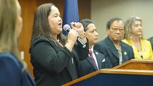 Speaker Muña Barnes standing with he colleagues on a podium.