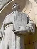 A statue at the Palace of Culture and Science (1955) in Warsaw, holding a book of works by Karl Marx, Friedrich Engels and Vladimir Lenin