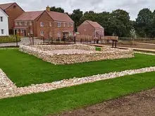 Low walls of flint creating an inner square chamber surrounded by an outer chamber