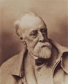 An elderly and extremely tired looking man with a thinning hair and a long white beard