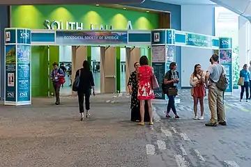 Entrance of a convention center room with meeting attendees preparing to enter.