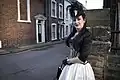 A goth woman wearing a black and white corset over a black blouse and white skirt.