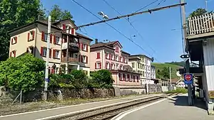 Side platform with tracks to either side and a row of buildings behind