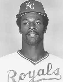 A man in a light baseball jersey and dark cap