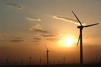 Photograph of wind turbines against a hazy orange sky (from Sustainable energy)