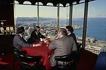 Photo of men dining at high-rise restaurant overlooking harbour