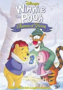 Pooh holds Kessie in brighten, he, Piglet and Tigger watches in happiness. A forest covered in snow view is behind them.