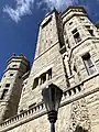 The front turrets, clock tower, and a gas lantern.