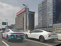 An itasha in Shanghai, China with Miku on a Xpeng P7 next to a regular Xpeng P7