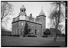 Conservatory of Yankton College, a late 19th century brick building, three stories, the third story having a mansard roof, with a four-story tower at one end and an ornate cupola at the other.