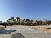 A fountain, and behind it a large rocky hill inside the park (2023)