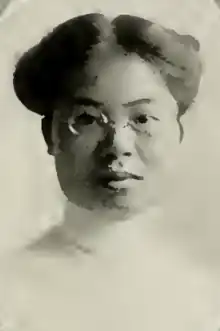 A young Chinese woman wearing eyeglasses and a high-collared white blouse; her hair is parted center and dressed in an updo