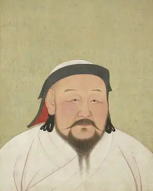 Portrait of a bearded man wearing white robes and a white and black headscarf.