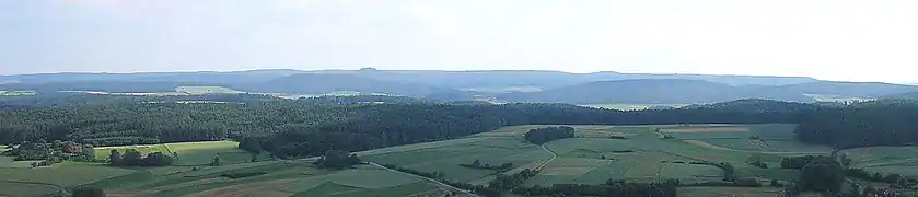 The rolling hills of the Haßberge from the eastern hillside of the  Zeilberge near Maroldsweisach. Centre left: the prominent volcanic cone of the Bramberg