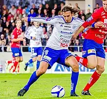 Vladica "Vlado" Zlojutro with the ball in front of him holding an opponent back using his left arm