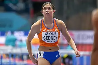 Photo of Zoë Sedney in orange and blue sportswear looking up