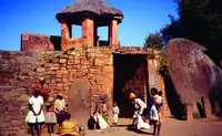 Tall opening through a wall of stacked rough-cut stones, with an enormous stone disk leaning against it to the right