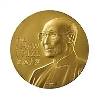 A gold circular medal with a depiction of an elderly man with glasses wearing a jacket buttoned to the neck; the English words "The Shaw Prize" and Chinese characters "邵逸夫獎" engraved on it