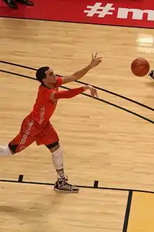 Jones, in a red jersey, lunges forward, tossing the basketball.