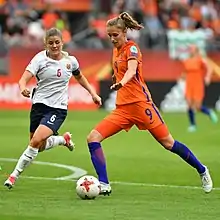 Two women in football kit with a ball