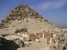 Eroded remains of a pyramid with twin columns marking the entrance to the main complex and causeway leading to it laid before it