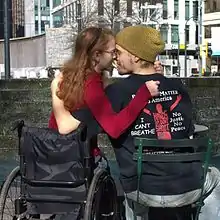 A woman in a wheelchair embracing a man in a chair