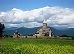 Church from far, field in front, hills in the back