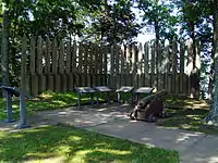 Wooden posts in a semicircle around information boards and a cannon