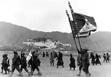 1938年新年在布達拉宮前接受校閱的藏軍官兵。右上可見雪山獅子旗