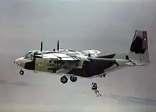 A military transport aircraft with a parachutist jumping from the rear