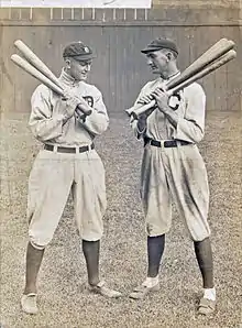 Two batters holding bats, conversing.