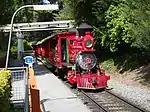 A red steam locomotive with a Template:Whyte wheel arrangement and its tender